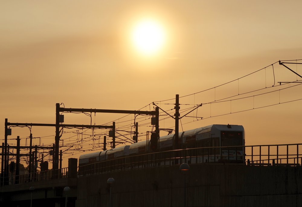A NJ Transit light rail train pulls out of the Hoboken transit terminal as the sun sets on May 10, 2023, as seen from Jersey City.