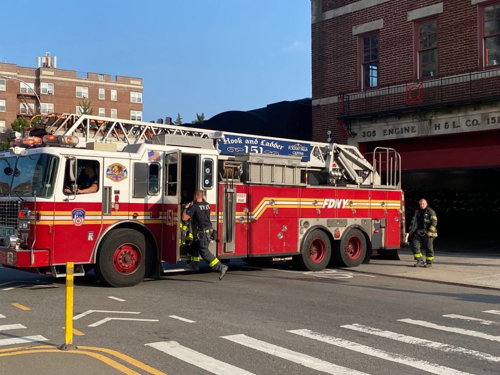 Firefighters jump onto an FDNY truck responding to a call.