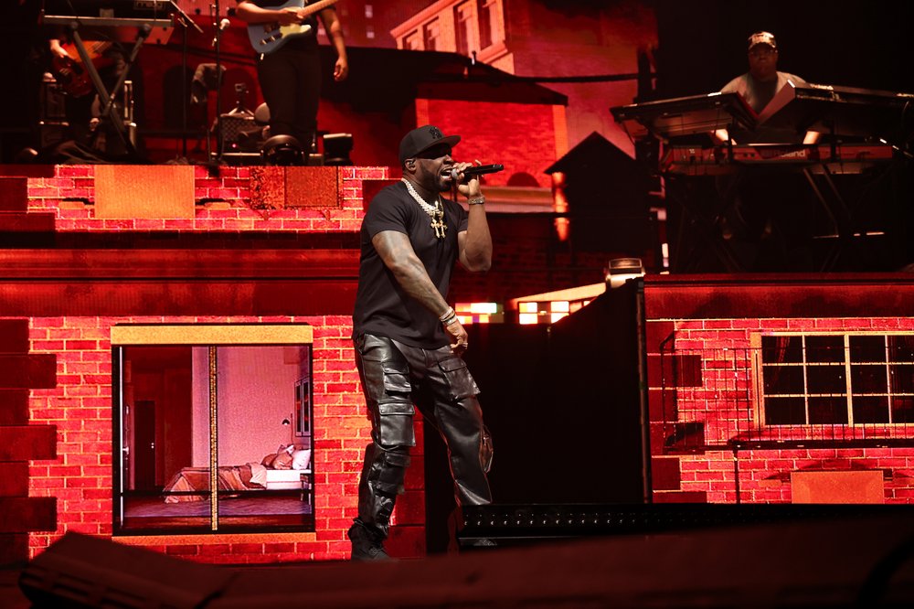 A singer dressed in all black performs on stage.