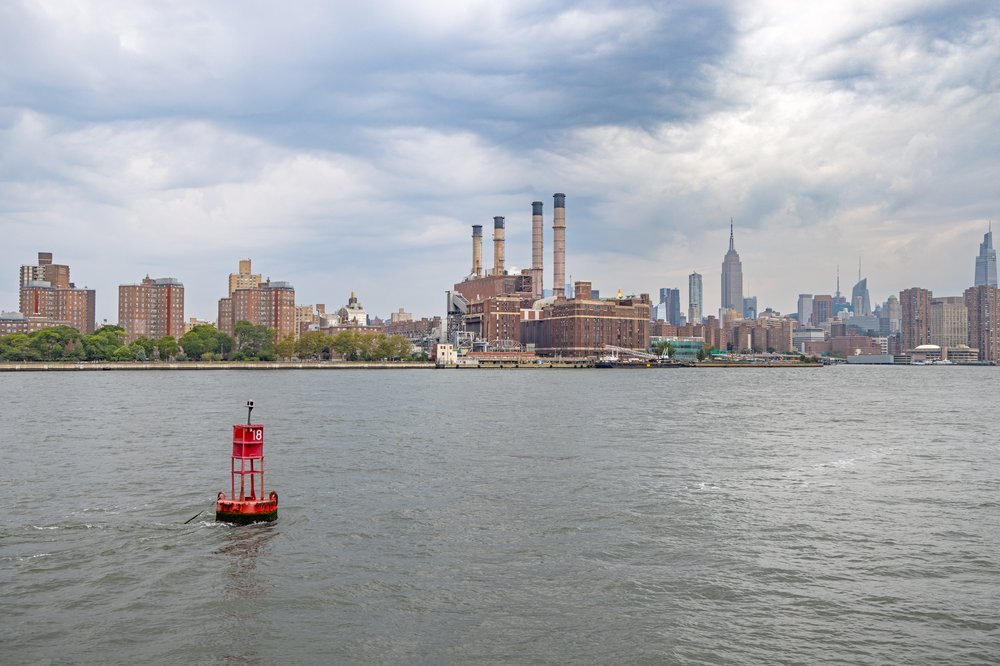 New York skyline with a floating buoy and a power plant in front.