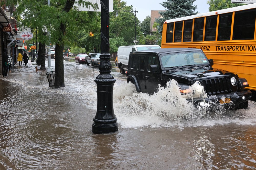 A jeep and school bus on a flooded Brooklyn road.