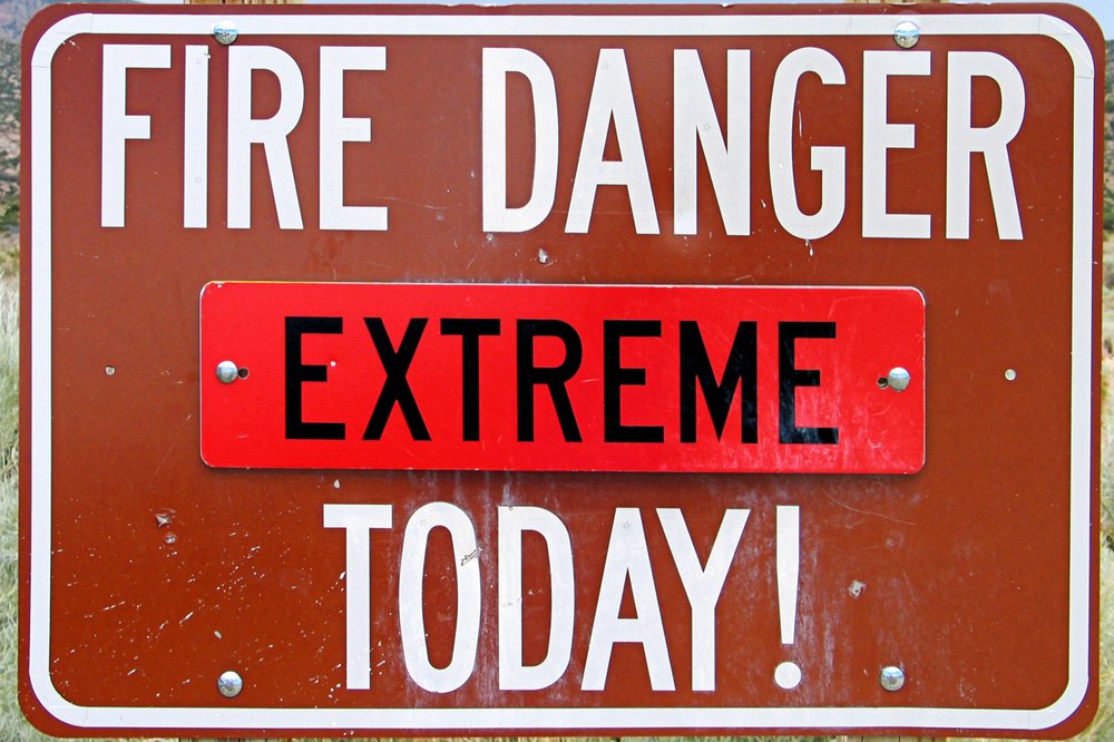 A sign in front of mountains warns of extreme fire danger.