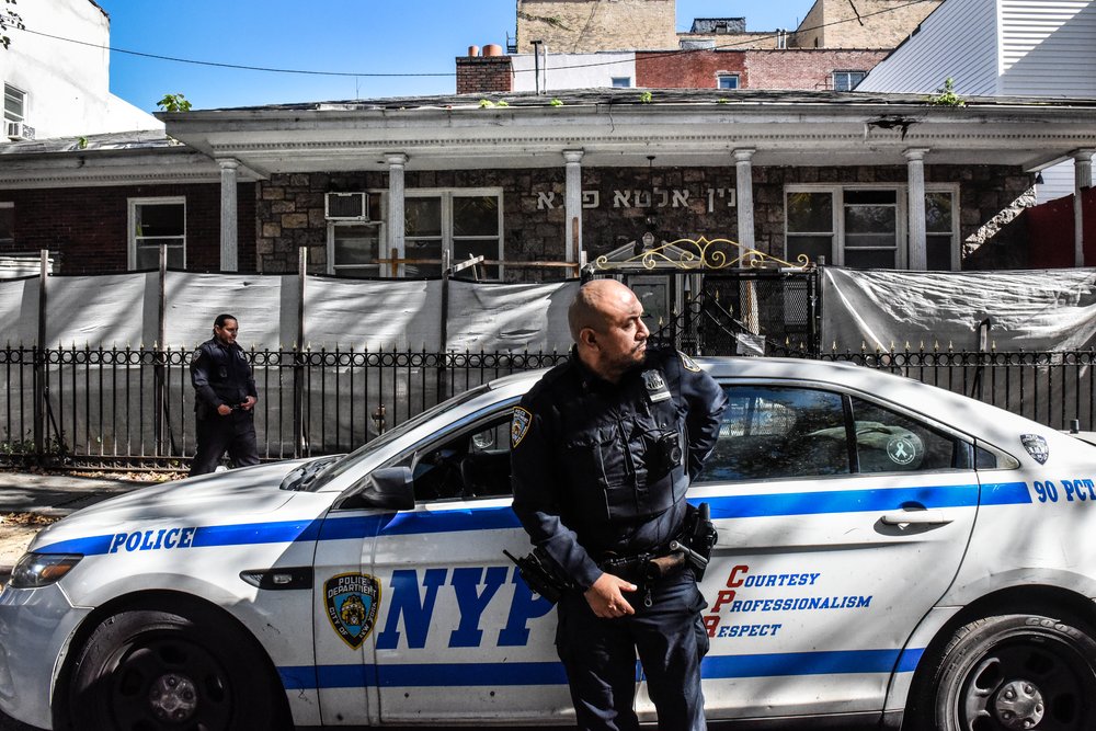 A New York Police Department officer stands in front of a synagogue on a Brooklyn street.