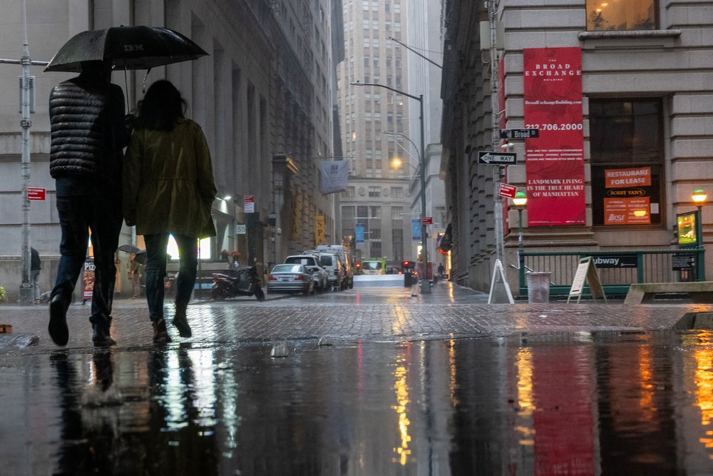 People walk through the morning rain by the New York Stock Exchange (NYSE) on October 20, 2023 in New York City.