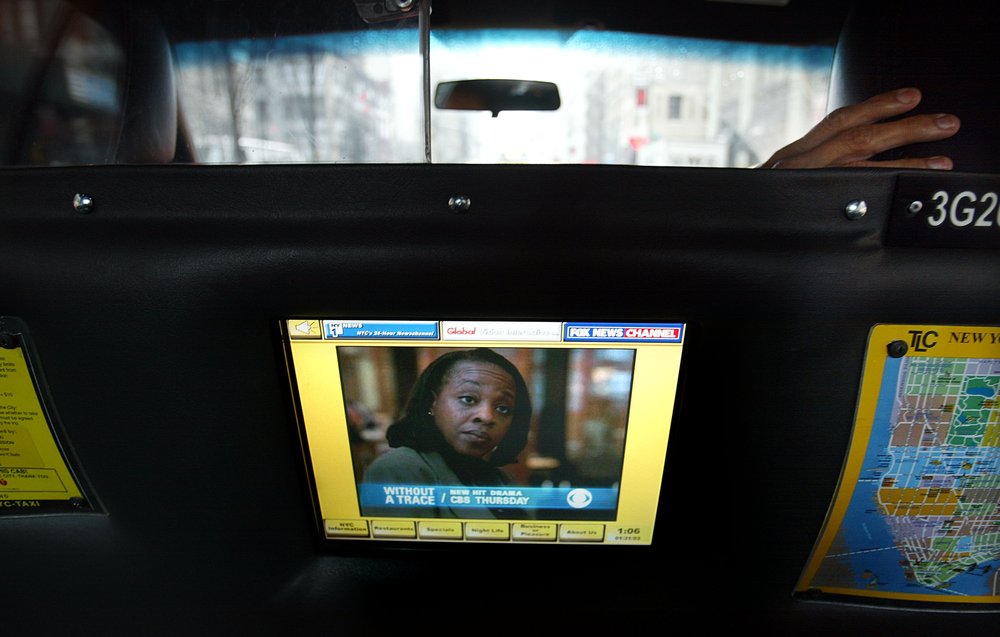 A TV screen in the back of a yellow cab