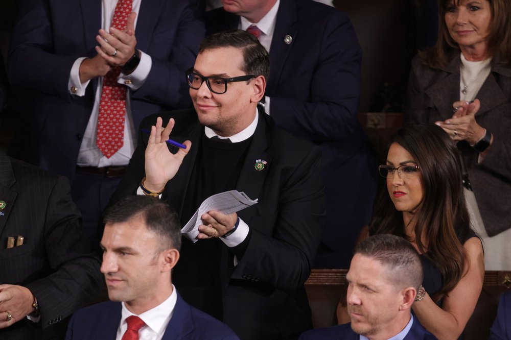 Rep. George Santos, standing next to Rep. Lauren Boebert, stand and applaud the new Speaker of the House.