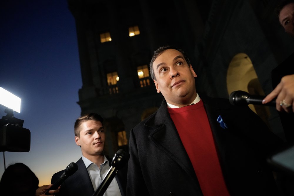 Rep. George Santos speaks to reporters outside of the U.S. Capitol in his signature red sweater.