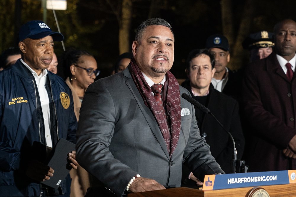 Edward Caban speaks at a press conference wearing a suit.