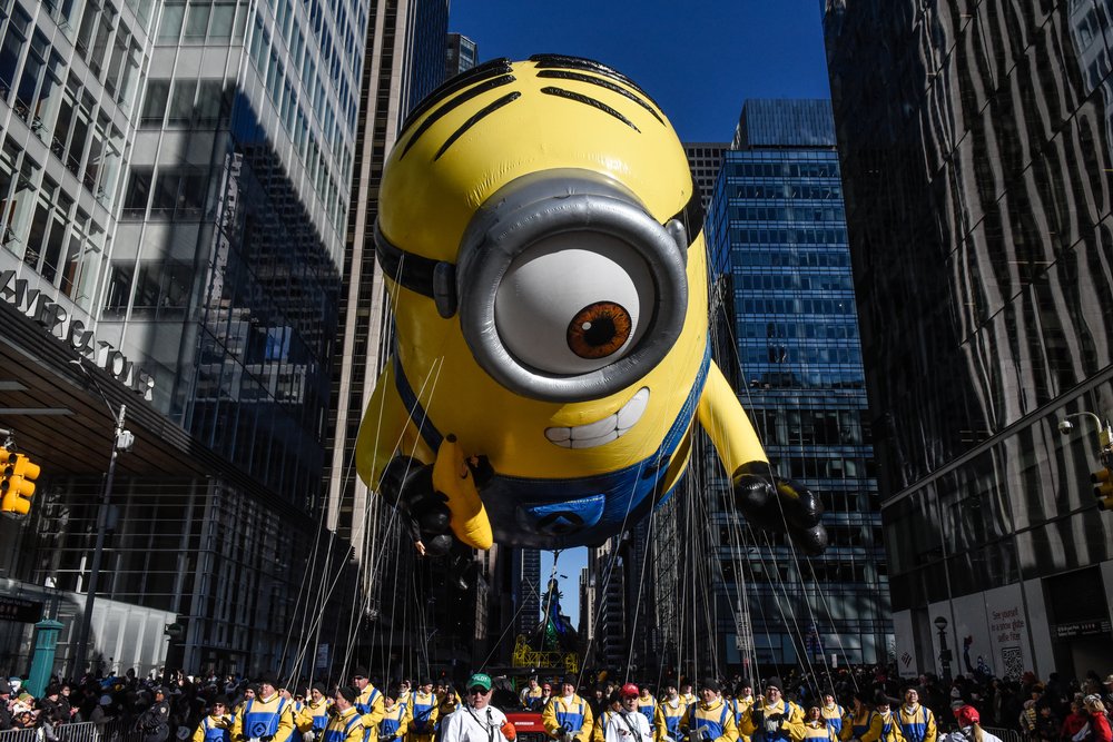 A Minions balloon hangs in the sky above a crowd.