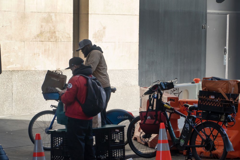 Two men wait for and repack orders prior to delivering them by bicycle.