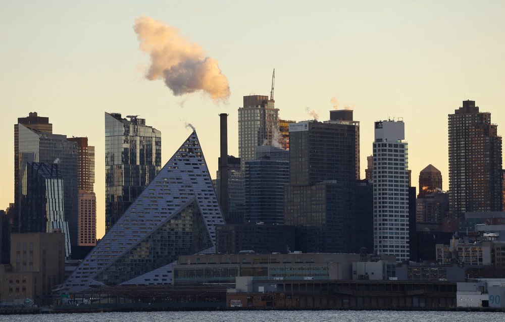 An emission rises out of a smoke stack in the west side of Manhattan as the sun rises in New York City.