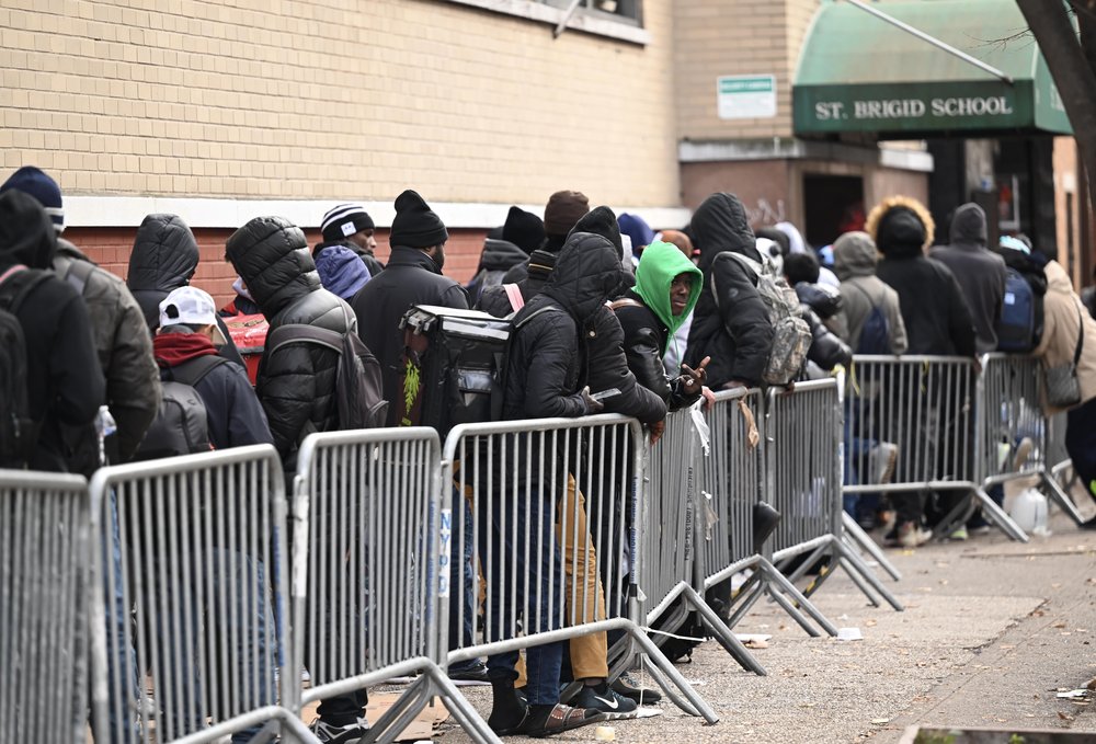 Migrants wait in line outside of a New York City building.