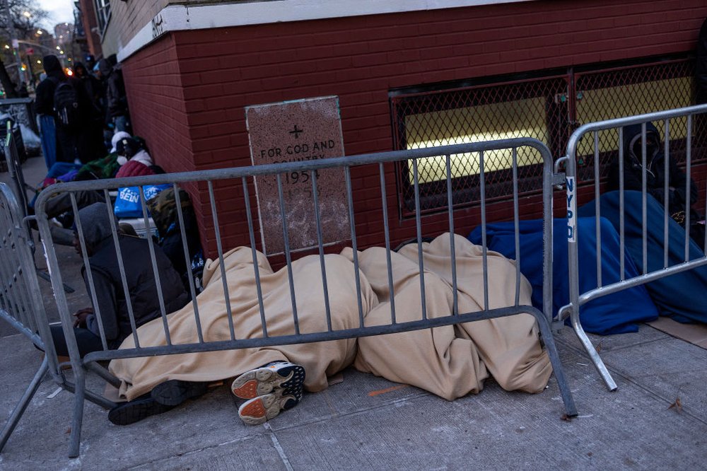 Migrants wait in a long line overnight hoping to receive a placement in a city shelter, in the East Village on Dec. 6, 2023.