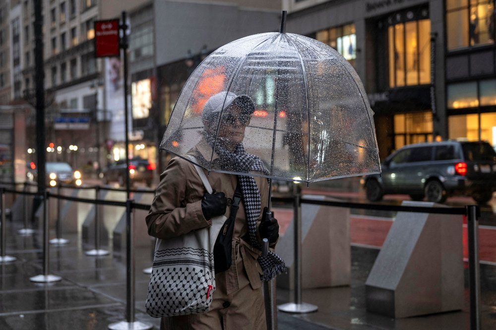 People with umbrellas walk through heavy rain in New York