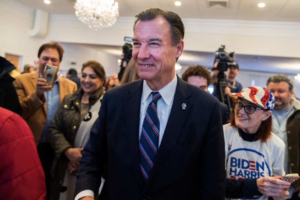 Former Rep. Tom Suozzi greets guests during a campaign rally at the Polish National Home in Glen Cove. He's wearing a suit and tie and there's a crowd behind him taking photos.
