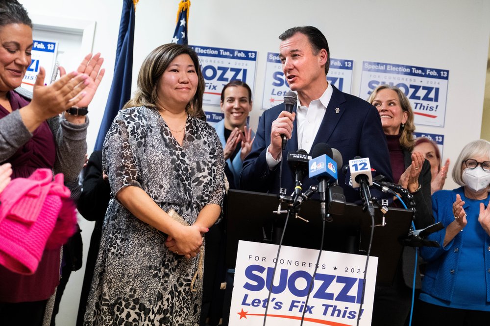 Democrat Tom Suozzi stands beside Rep. Grace Meng at a podium.