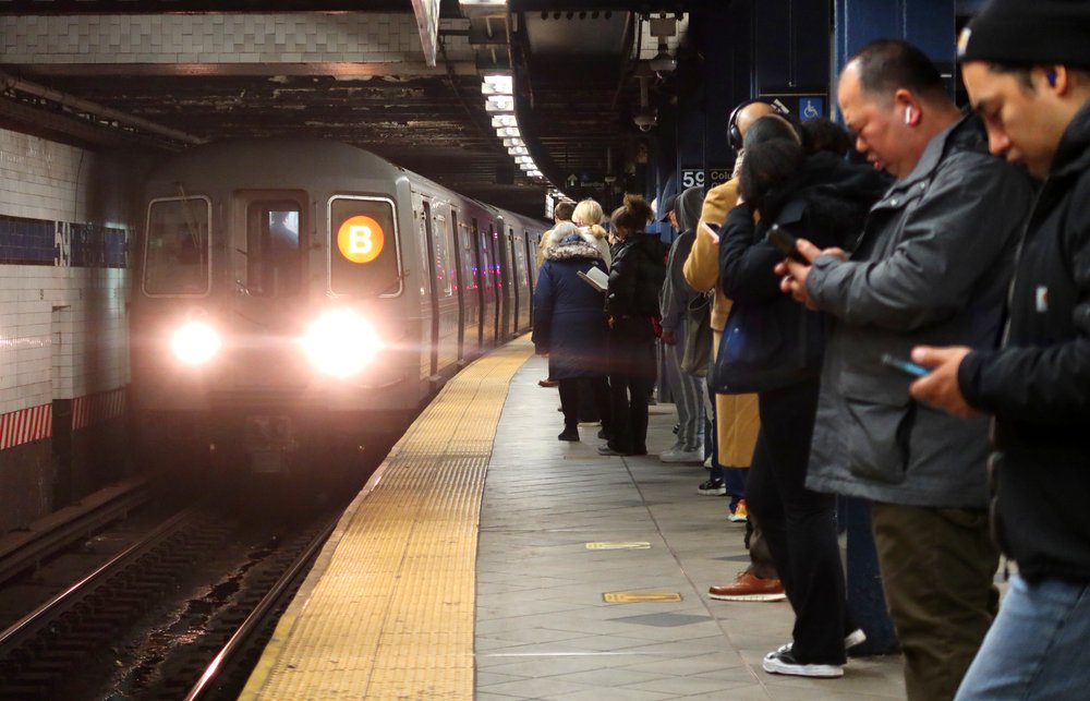 Subway riders standing on a platform at Columbus Circle as a B train pulls in.