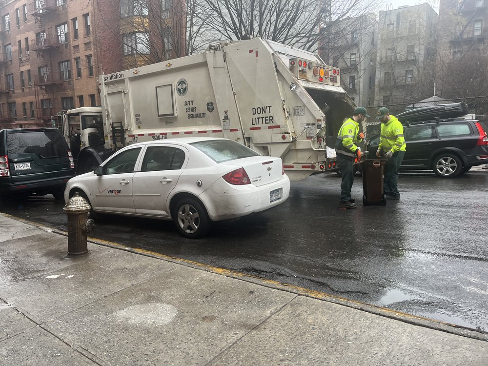 Sanitation workers hauling compost into a truck.