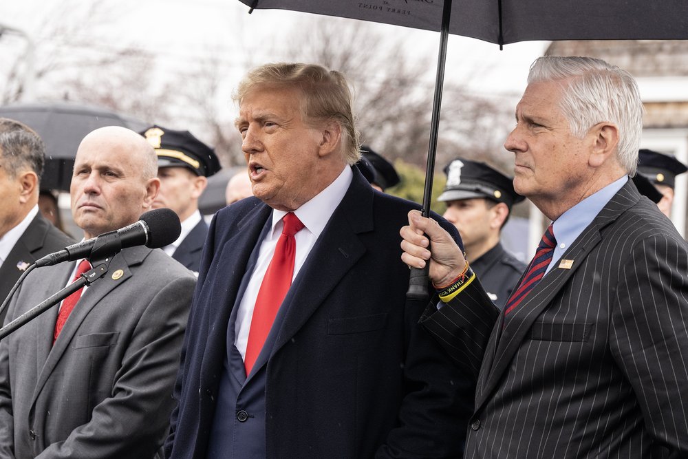 Nassau County executive Bruce Blakeman holds an umbrella over Donald Trump
