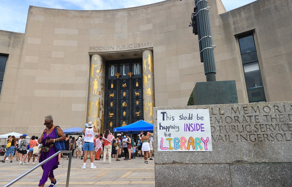 With protests gathered outside the Brooklyn Public Library, a says "this should be happening INSIDE the library."