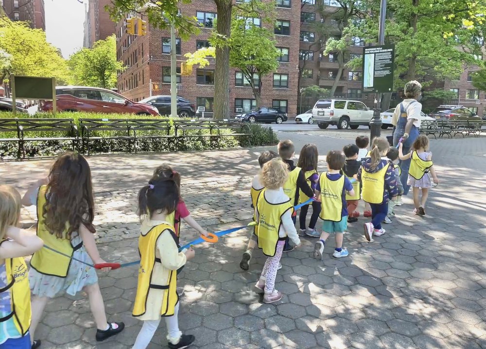 Children from Bright Horizons daycare hold onto a cord as they walk outside in New York City to ensure they stay together with their group and supervisor.