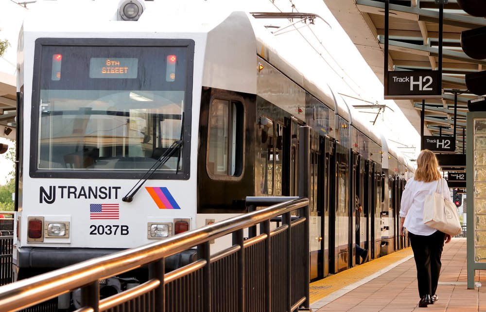 A woman walks to a NJ Transit light rail train.