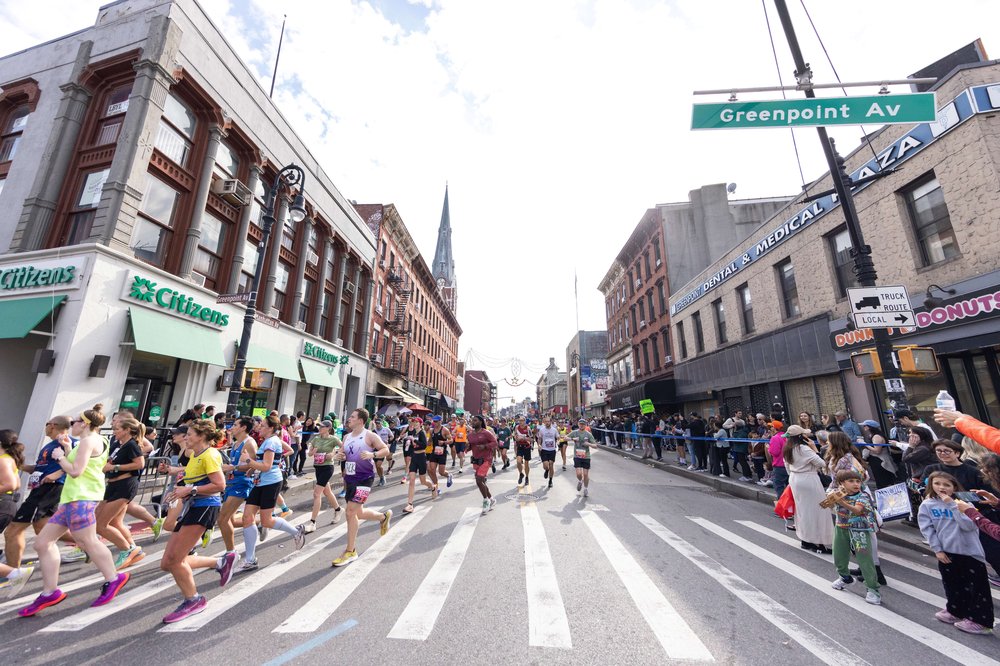 People run in the streets while spectators cheer them on.