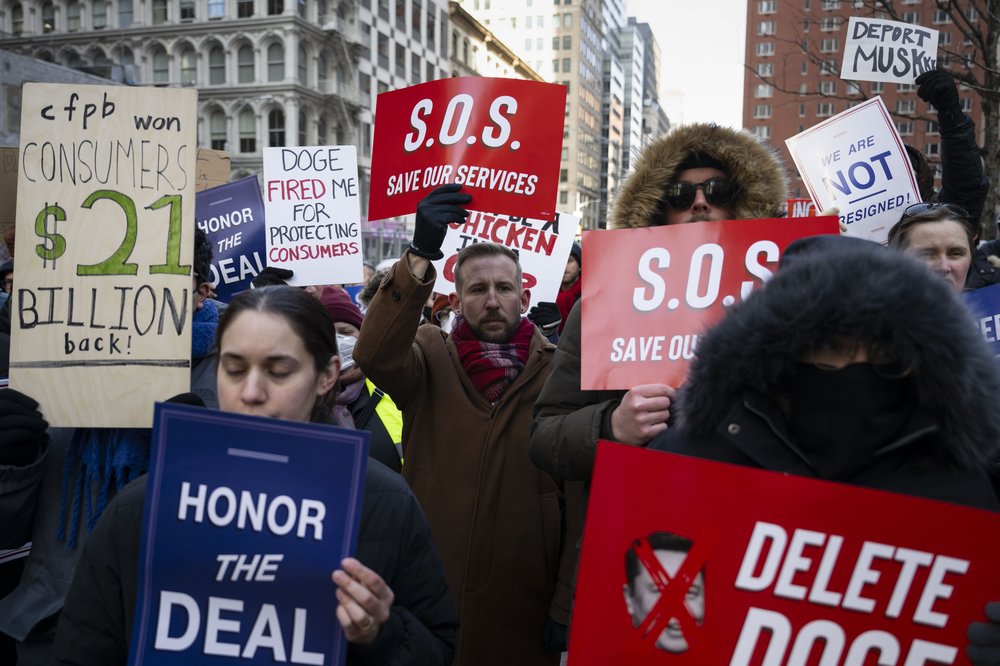 People holding banners chant during a rally outside the Jacob K. Javits Federal Building against the firings of thousands of federal workers by U.S. President Donald Trump and Elon Musk's Department of Government Efficiency (DOGE) in New York City on Feb. 19, 2025.