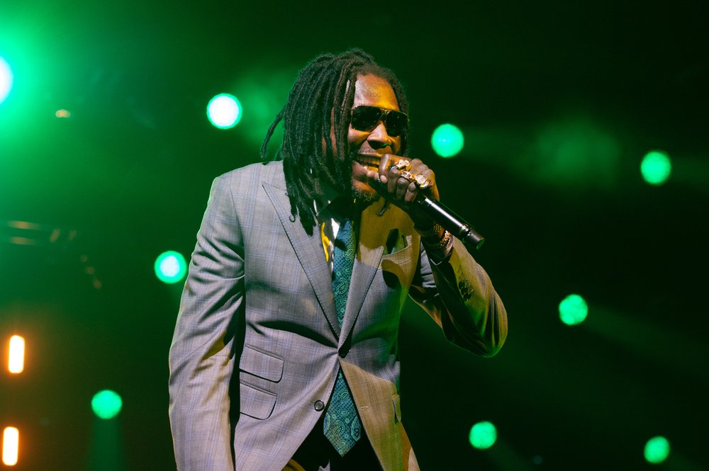 A man stands on stage in a suit holding a microphone.