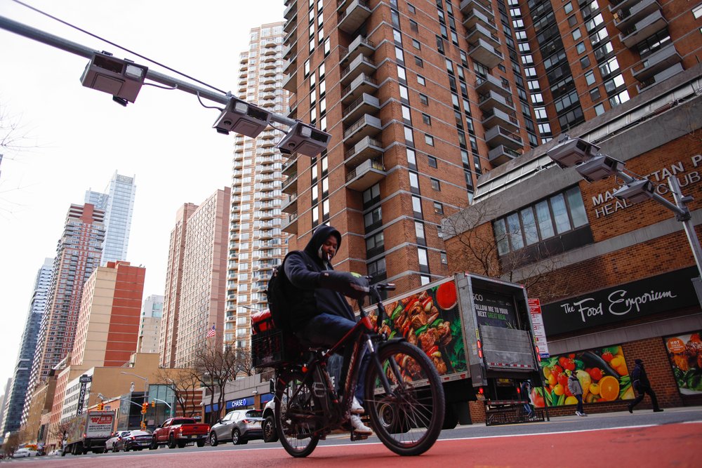 A man riding a bicycle under the MTA's congestion pricing readers.