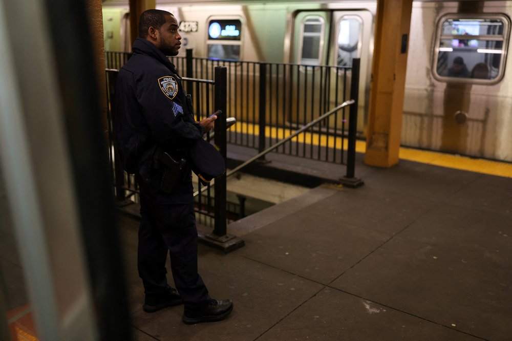 An NYPD officer patrols on a subway train platform.