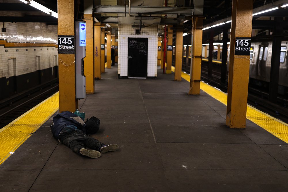 A man laying on a subway platform.