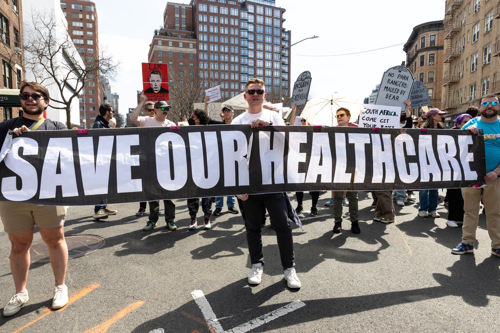 People march in protest against Tesla CEO Elon Musk and the Trump administration on March 29, 2025, in New York City. Activists and community members protested on the 38th anniversary of ACT UP/New York, marching to a Tesla dealership against cuts by the Trump administration, led by Musk's Department of Government Efficiency and Human Services Secretary Robert F. Kennedy Jr. The themed rally, "Death By 1000 Musk Cuts," aimed to gather 1,000 participants, each representing an employee who lost their job in programs impacting public health and health care. Thousands of employees across the federal government have left their jobs, been put on leave, or been fired as a part of the government-gutting initiative of the Trump administration and billionaire Musk.