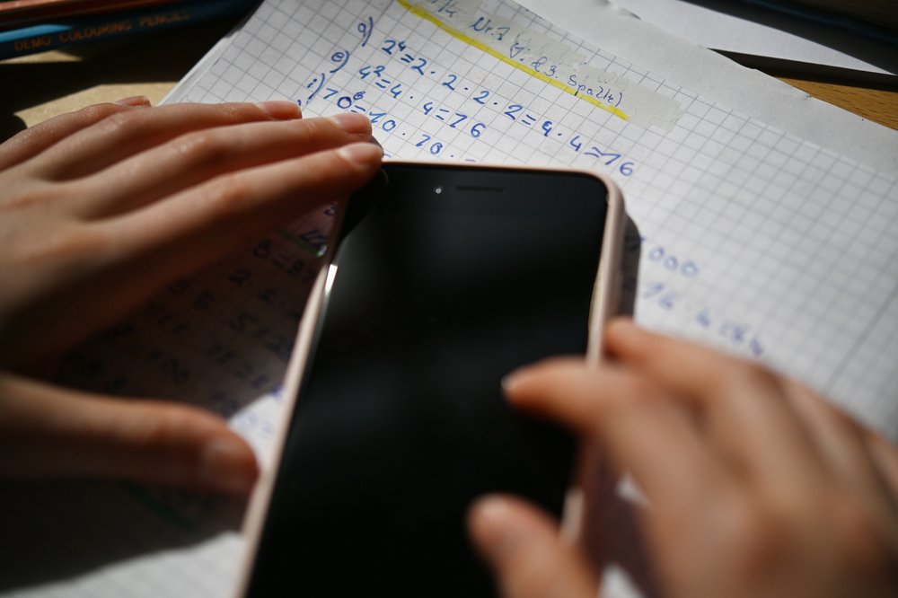 An iPhone next to paperwork with math problems.