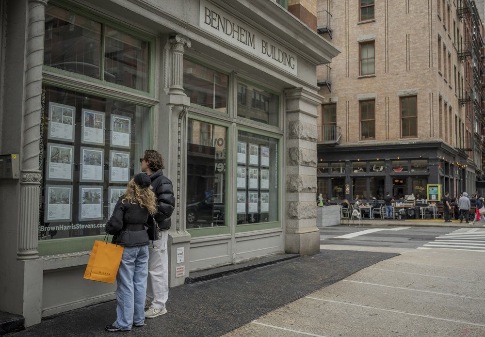A couple view properties for sale in the window of a real estate agent in the Tribeca neighborhood in Manhattan.