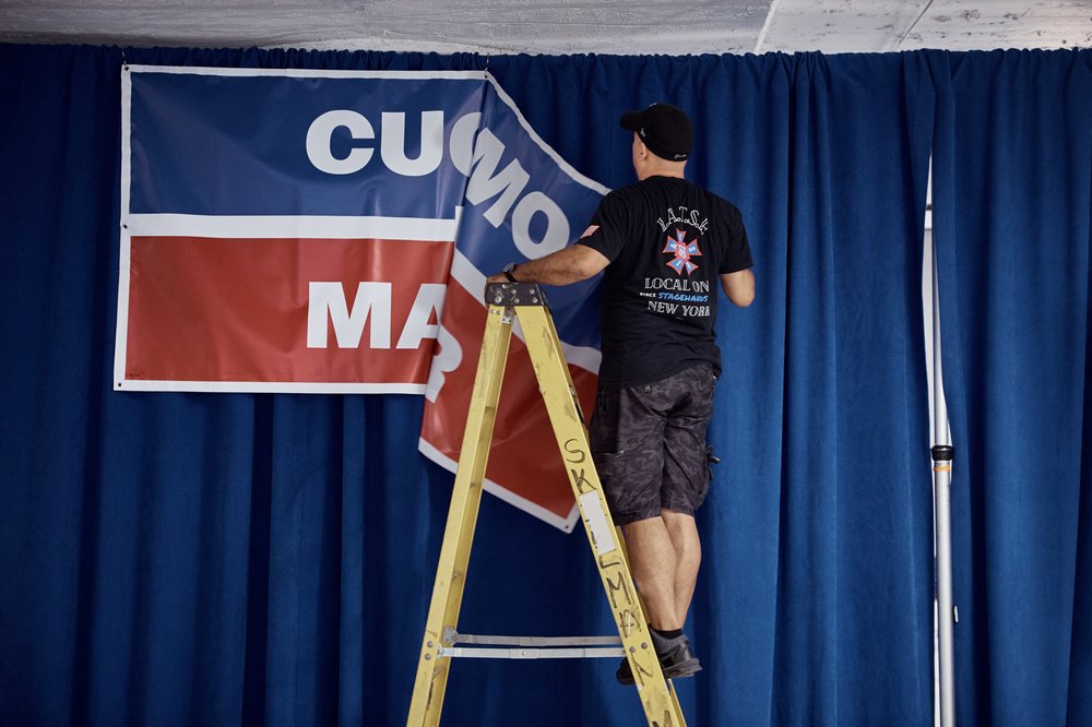 Workers pull down a "Cuomo for mayor" sign.