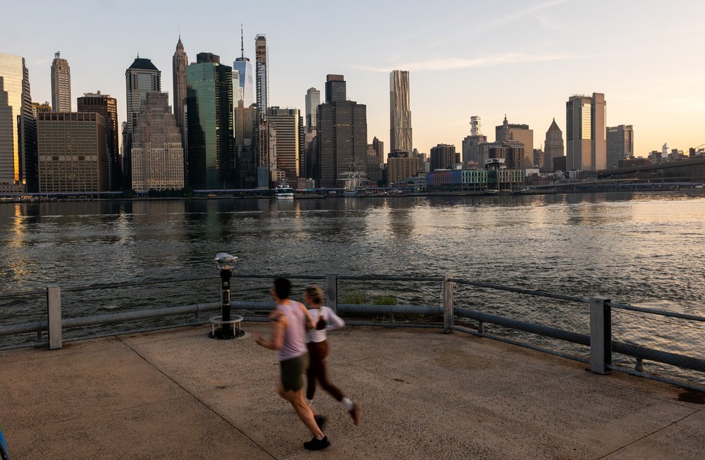 Runners run along the East River in Brooklyn, with the Manhattan skyline in the background, on June 24, 2025.