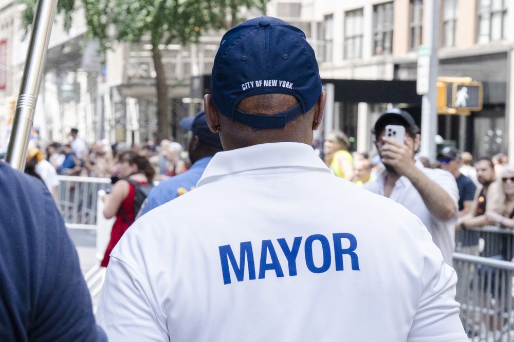 Mayor Adams walks in a parade wearing a "Mayor" shirt.