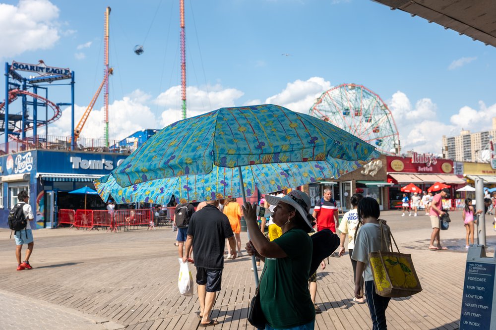 A woman sells an umbrella on the Coney Island boardwalk on July 8, 2025.