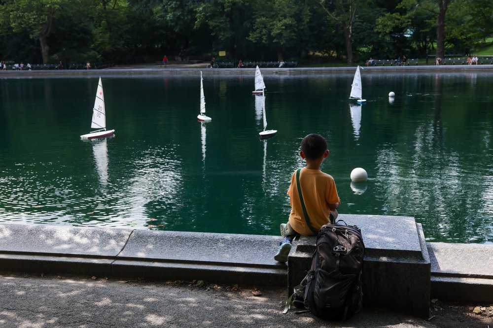 A boy watches sail boats in a pond at Central Park in Manhattan on July 17, 2025.