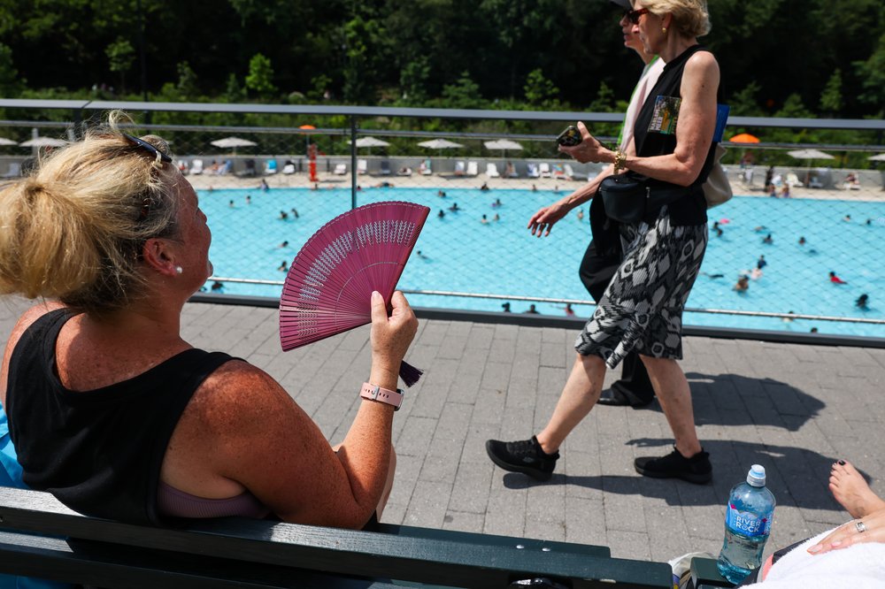 A woman fans herself overlooking the Davis Center in Harlem Meer on July 17, 2025.