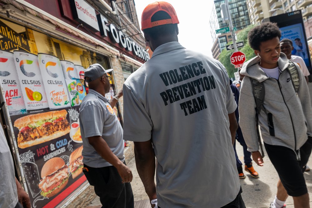 Members of a violence prevention team gather near a hookah lounge where three people were shot dead and 10 others wounded following a shooting at the Taste of the City lounge in Crown Heights, Brooklyn, early Sunday on August 19, 2025, in New York City. Police, anti-violence activists, and others have been making a strong presence in the neighborhood, which has experienced a number of shootings over the years.