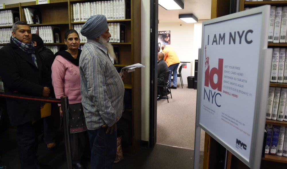 People wait in line to be processed for their New York City municipal ID cards January 14, 2015 at a midtown library in New York. One piece of plastic, but its going to open so many doors for our fellow New Yorkers, New York mayor de Blasio said at the Flushing branch of the Queens Public Library, one of 11 locations where the cards will be available.