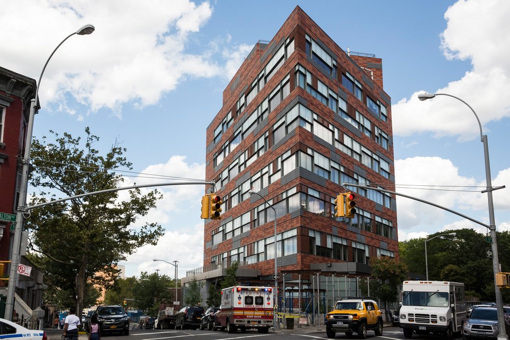 The PATH Intake Center at 151 East 151st St. in the Bronx, a tall brick building with wrap-around windows.