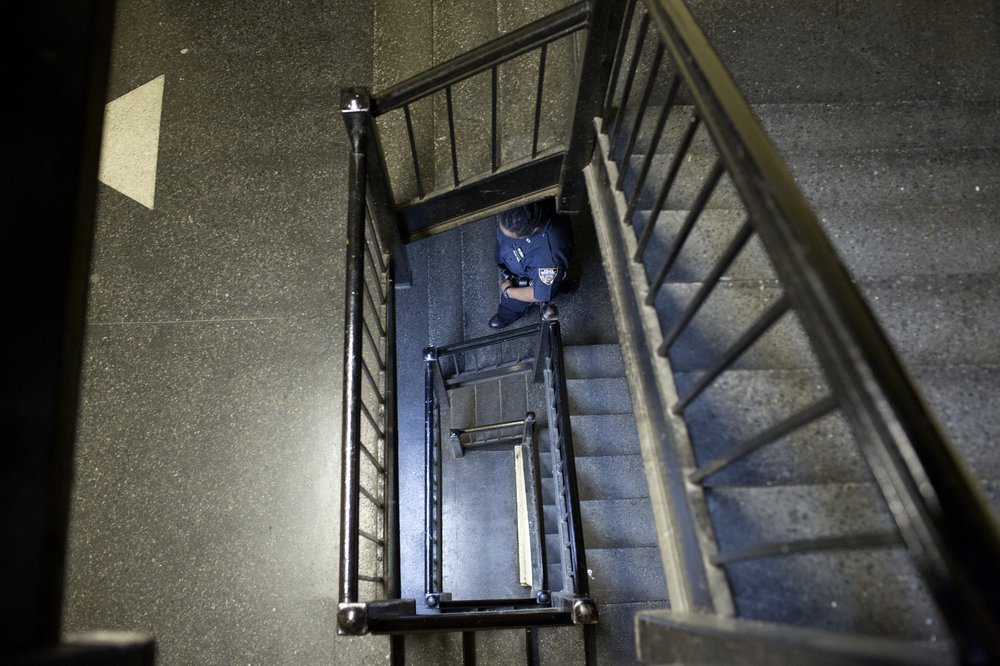 An NYPD officer from the 67th precinct patrols the stairwell of a building in East Flatbush.