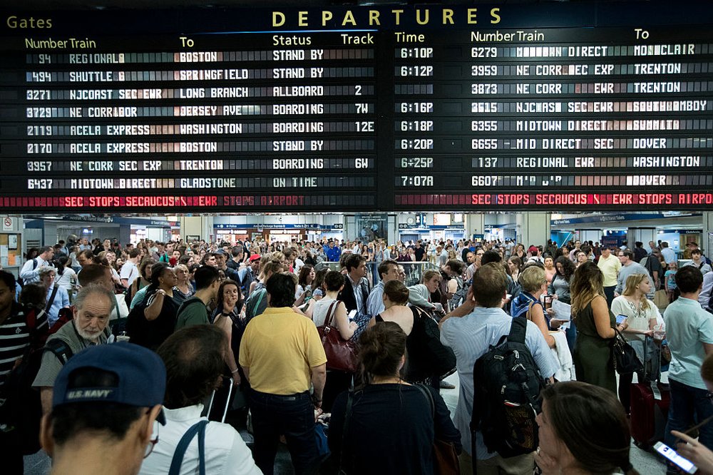Hundreds of people gather around the old departures board at Penn Station.