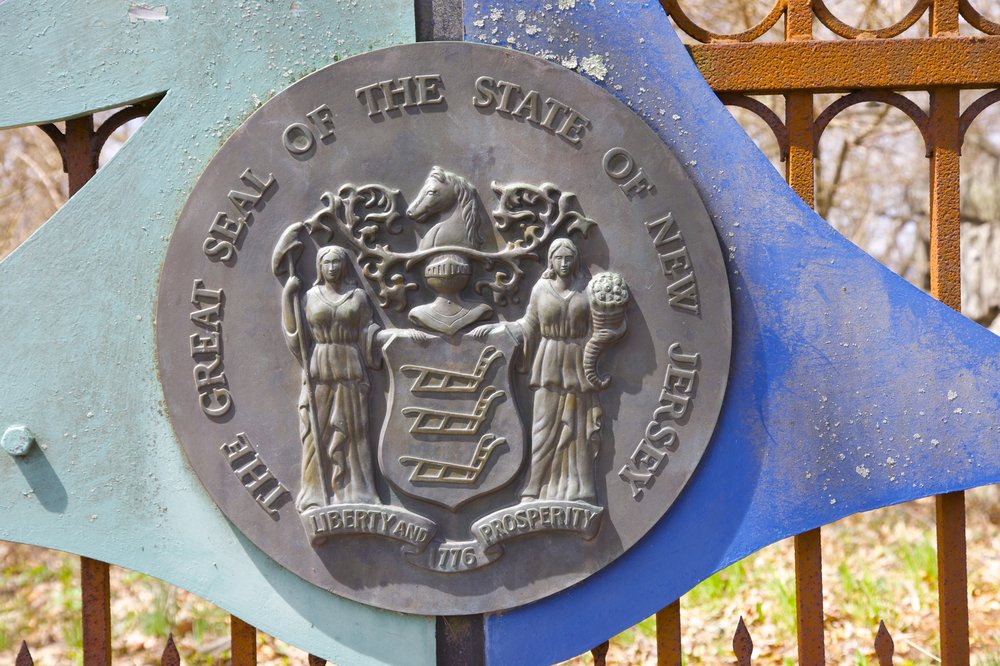 An iron replica of the New Jersey seal on a gate in a state park.
