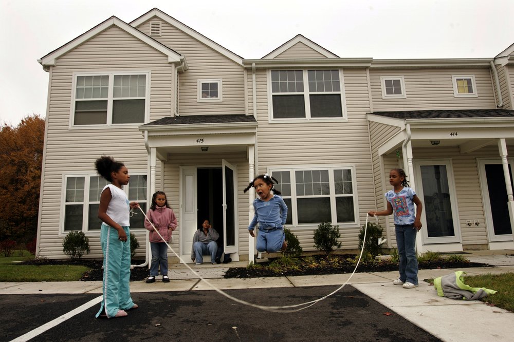 Young people jump rope outside of their home.