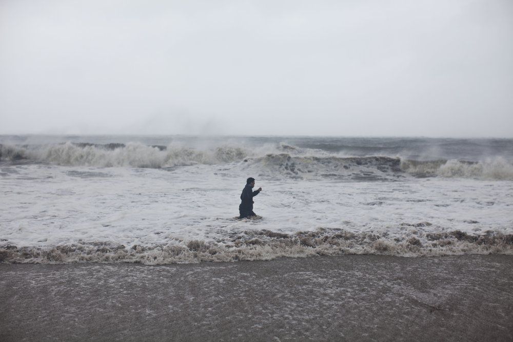 A man in rough water off the coast of Coney Island.