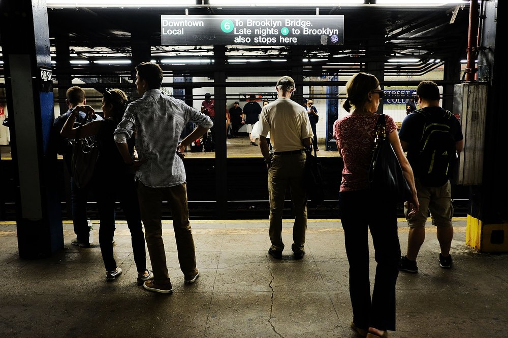 People wait for a downtown 6 train to arrive.